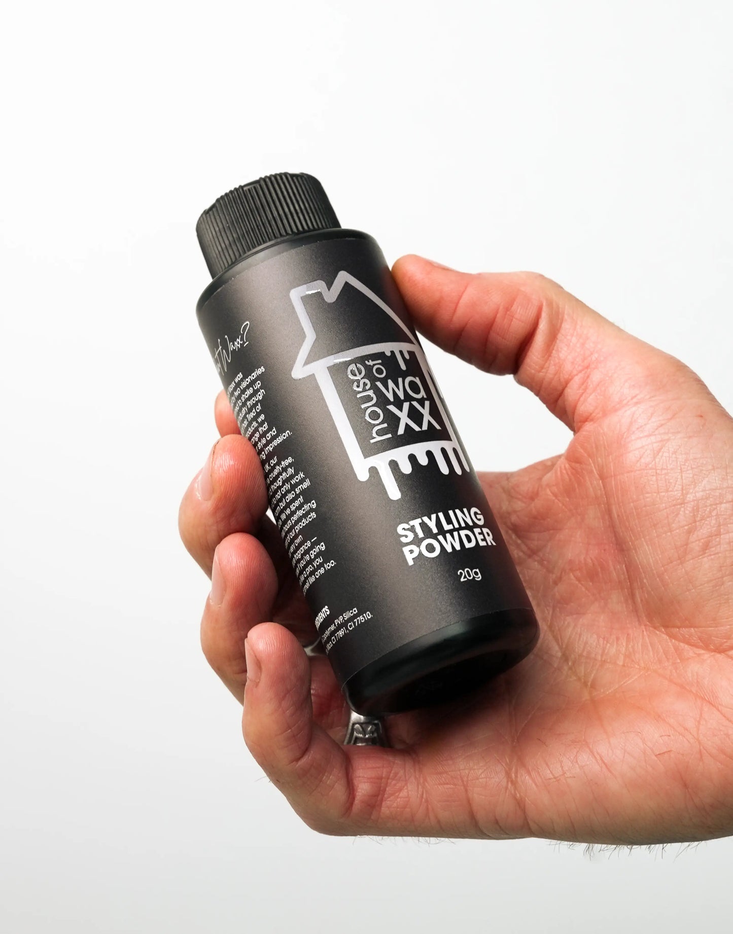 Hand holding a bottle of House of Waxx Styling Powder 20g, on a white background